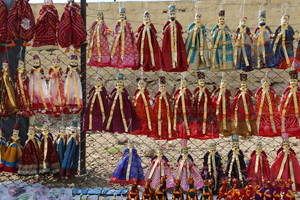 Many colorful puppets are displayed for sale.
